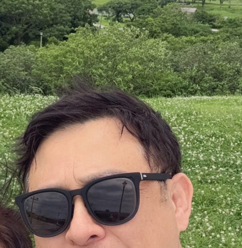Siyah çerçeve takan bir müşteri, yeşil bir çayırda selfie çekiyor